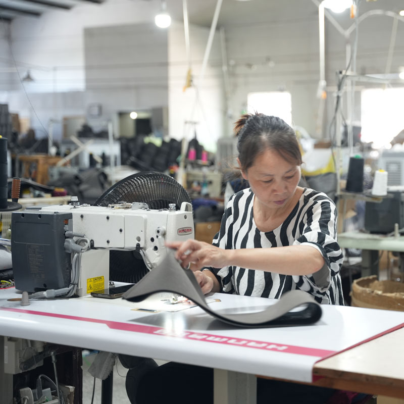 Worker sewing a custom steering wheel cover at an automotive accessories manufacturing facility